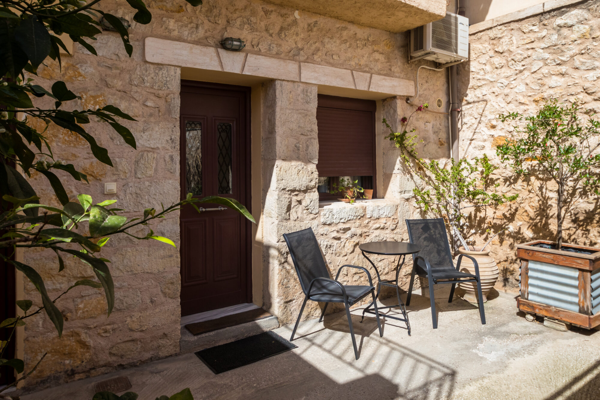 Αυλή με πετρόκτιστο κτίσμα με καρέκλες και ένα τραπέζι